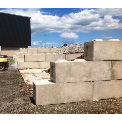 Large C&O concrete interlocking blocks forming a retaining wall at an industrial yard