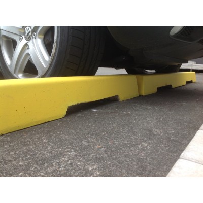 Yellow concrete wheel stops under a parked car