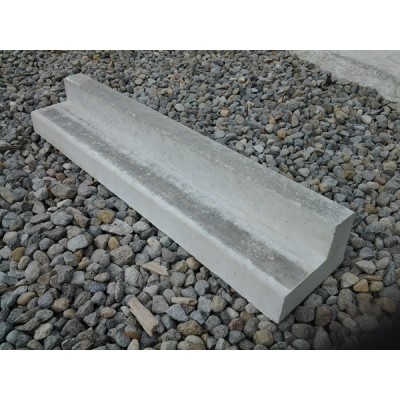 Single L-shaped concrete kerbing piece on gravel