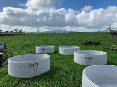 Round concrete water troughs stamped C&O in a green Taranaki paddock