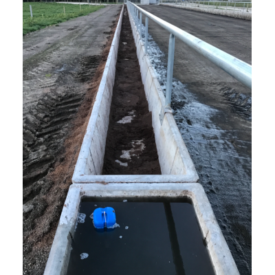 Long oblong concrete water trough along a stock rail