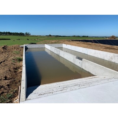 Concrete storage pond with free standing walls partially filled with water